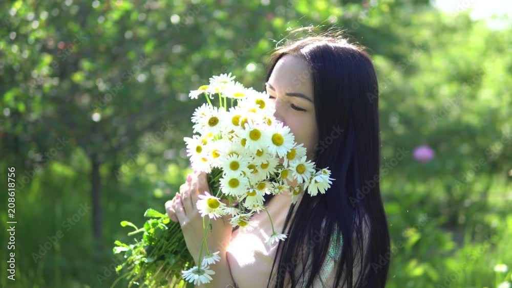 Beautiful brunette girl collects daisies and admires them. Beautiful brunette girl collects daisies and admires them.