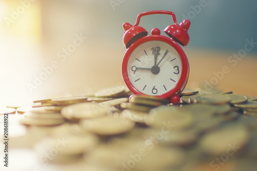 Stacking coins on desk with clock. Finance and money concept