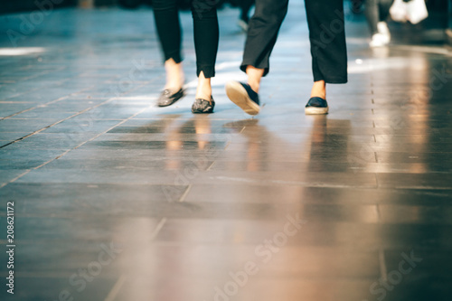 Blurred motion of people legs walking on pavement with copy space