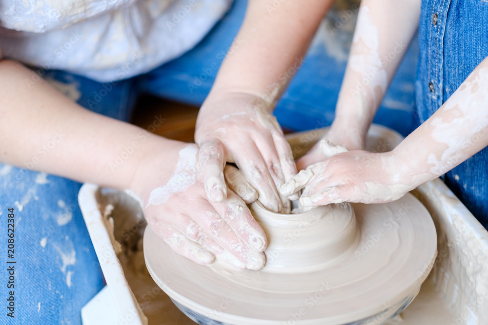 handmade hobby pottery courses. master class at workshop. potter forming clay on turning wheel with a little student kid