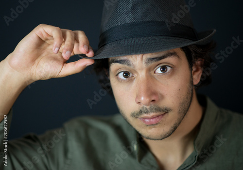 A nice young man, 20Y, is posing in studio with a hat. Black background. photo