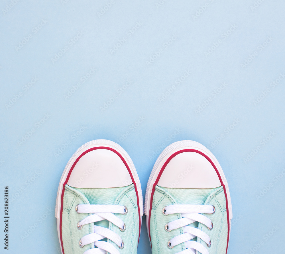 Pastel turquoise female sneakers on blue background. Flat lay, top view minimal background. Fashion blog or magazine concept. Pastel turquoise female sneakers on blue background. Flat lay, top view minimal background. Fashion blog or magazine concept.