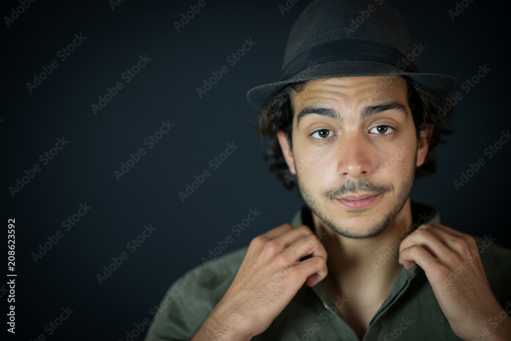 A nice young man, 20Y, is posing in studio with a hat. Black background. A nice young man, 20Y, is posing in studio with a hat. Black background.