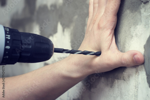 Drill in the hands of security. Drill wounded arm. The concept of safety in construction.