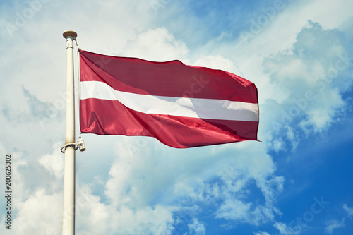 Canvas Print National flag of Latvia on flagpole against cloudy sky