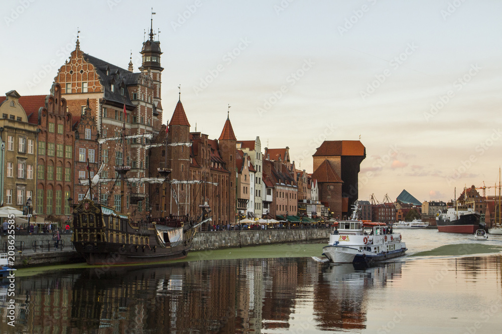 Ancient colored houses on the promenade of the river in Gdansk at sunset. Poland