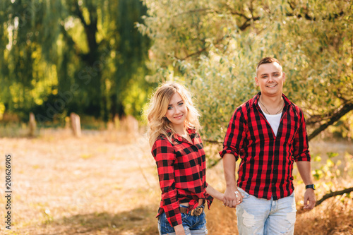 Valokuva Young couple dressed in identical red shirts, walking outdoors.