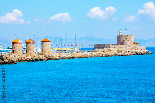Fototapeta Naklejka Na Ścianę i Meble -  Historic windmills at Mandraki port and Fortress Agios Nikolaos in Rhodes Town, Mediterranean Sea, Rhodes Island, Greece