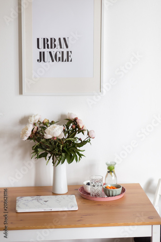 Arbeitsplatz mit Blumen Pfingstrosen und Wasser Snacks Laptop