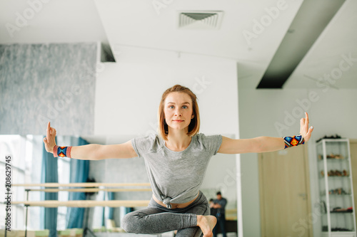 Sensual young woman is standing in yoga position and smiling. She is stretching arms sideways and looking forward with happiness photo