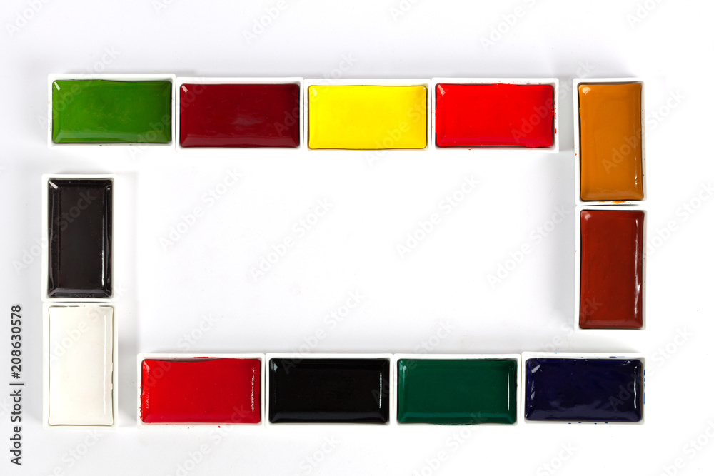 Fototapeta premium Colorful solid watercolor pans set making a frame with copy space on white background