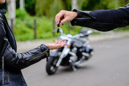 Hands give the keys to the motorbike. The concept of selling and renting motorcycles.