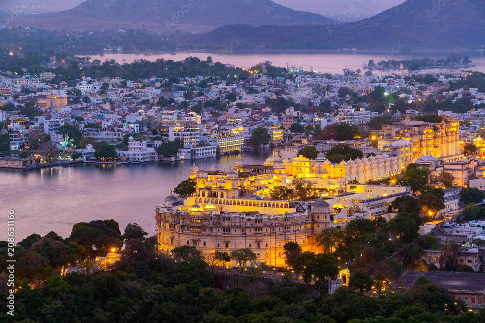 Fototapeta premium Udaipur city at lake Pichola in the evening, Rajasthan, India. View from the mountain viewpoint see the whole city reflected on the lake.