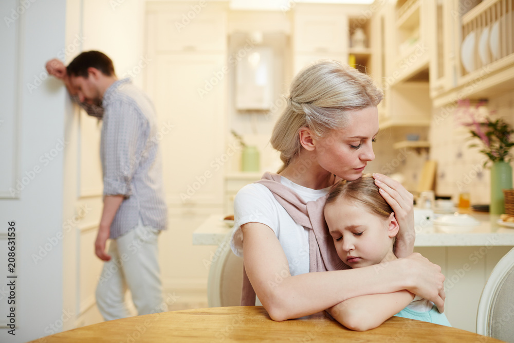 Young woman embracing and comforting little daughter after quarrel with husband Young woman embracing and comforting little daughter after quarrel with husband
