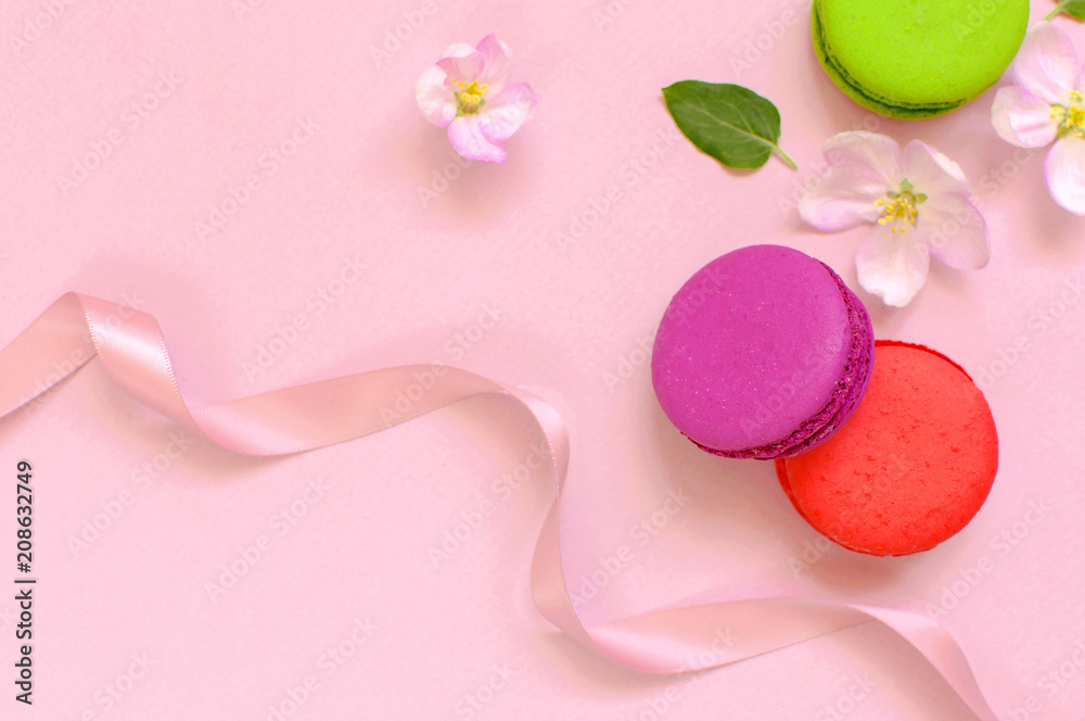 Cake macaron or macaroon with pink gift ribbon spring flowers on pink background top view flat lay, beautiful dessert, colorful almond cookies, pastel colors Cake macaron or macaroon with pink gift ribbon spring flowers on pink background top view flat lay, beautiful dessert, colorful almond cookies, pastel colors