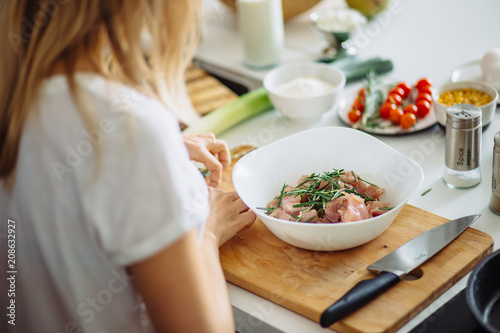 Home cozy kitchen chef female making pickled turkey meat with rosemary leaves. Barbecue concept or healthy meat lifestyle shot photo