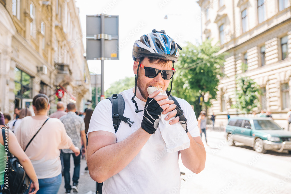 young adult bicyclist take a pause to eat. street food kebab young adult bicyclist take a pause to eat. street food kebab