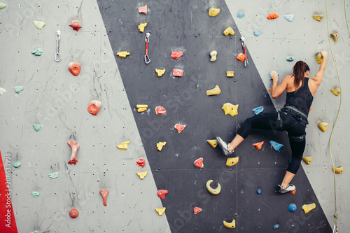 Sporty young woman training in a colorful climbing gym. Free climber girl climbing up indoor photo