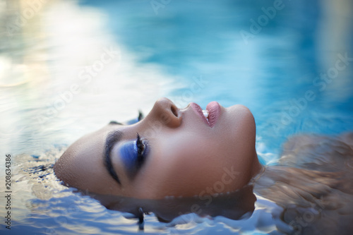 Beautiful long hair female model posing in the pool, outdoor portrait