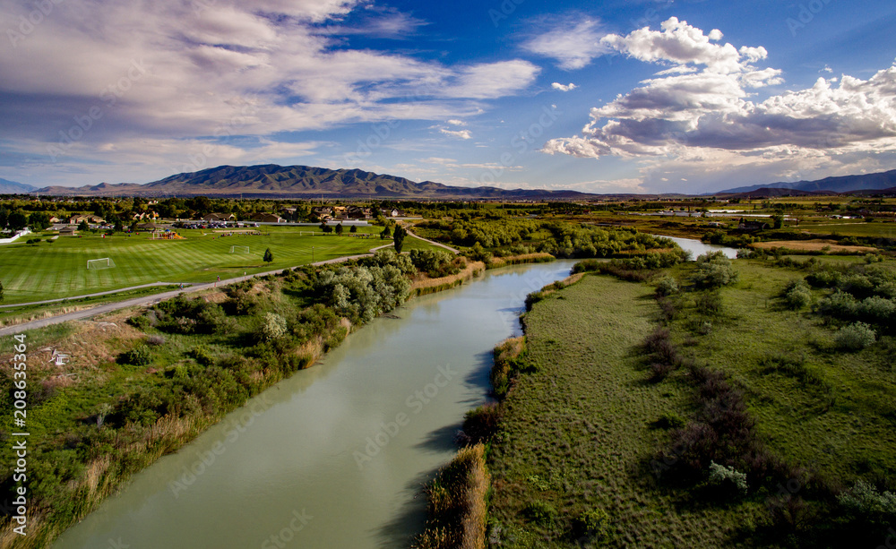 Aerial view of a river and golf course with mountains in the distance