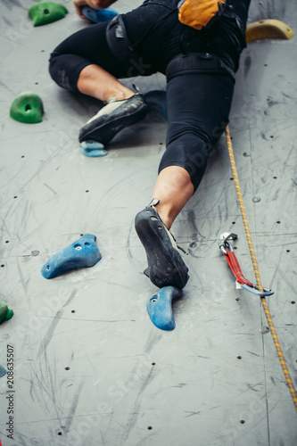 Feet of female climber in mountain boots on artificial boulder. Close-up bottom view of professional shoes photo