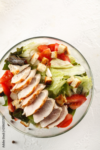 salad cesar with chicken grill in glass bowl on white table. Top view. Flat lay. Copyspace