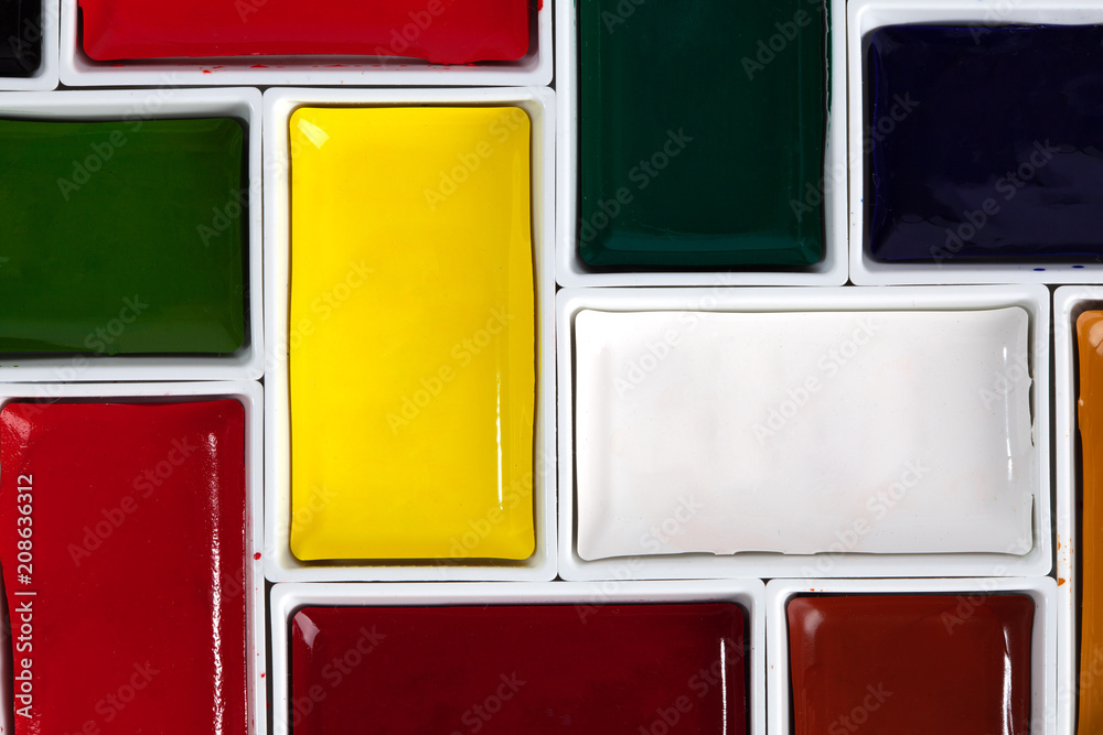 Colorful watercolor pans arranged in jigsaw puzzle top view with copy space