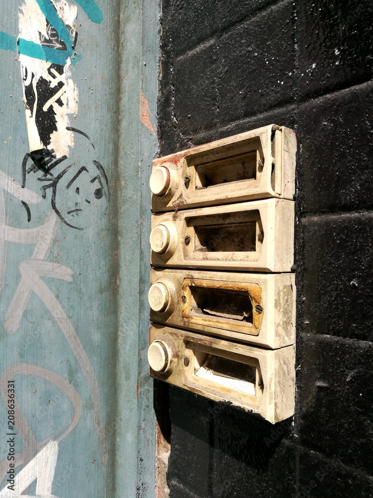 Φωτογραφία Vergammelte alte Türklingel in Beige auf schwarzer Wand an der Tür eines leerstehenden Haus im Sommer bei Sonnenschein an der Reeperbahn im Stadtteil St