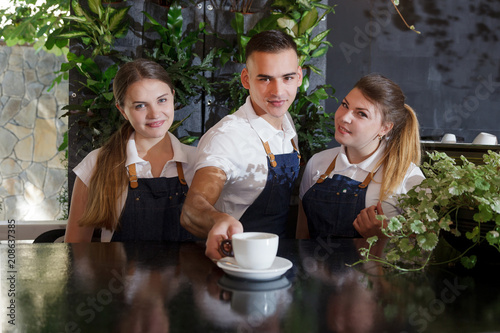 waiter green white leaves coffee cup portrait young male barista service coffee customer cafe apron female girl boy