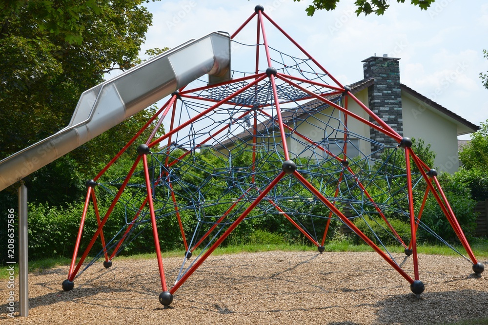 Großes Kletternetz mit Rutsche auf dem Spielplatz eines Wohngebietes Großes Kletternetz mit Rutsche auf dem Spielplatz eines Wohngebietes