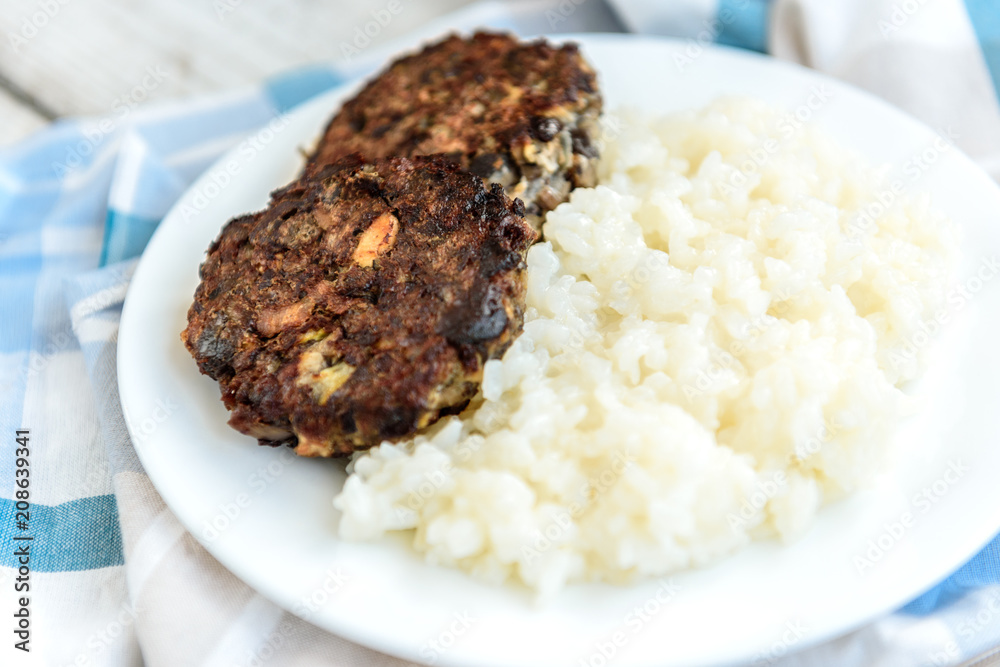 Homemade mushroom cutlets with rice porridge on wooden background. Healthy food for lunch or dinner. Homemade mushroom cutlets with rice porridge on wooden background. Healthy food for lunch or dinner.