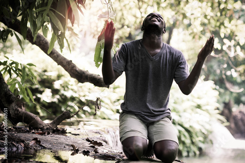 African man spiritual peaceful praying and wishing in green nature.