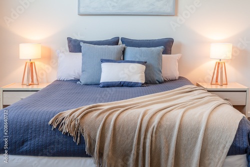 Fotografia Beautiful arrangement of pillows on bed in a bedroom with bedside lamps and copy
