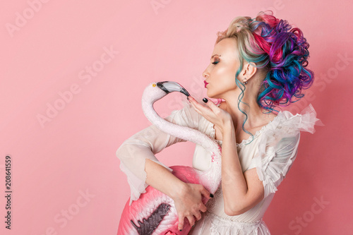 Stylish and beautiful woman with colored hair. Hugging a pink Flamingo figure.