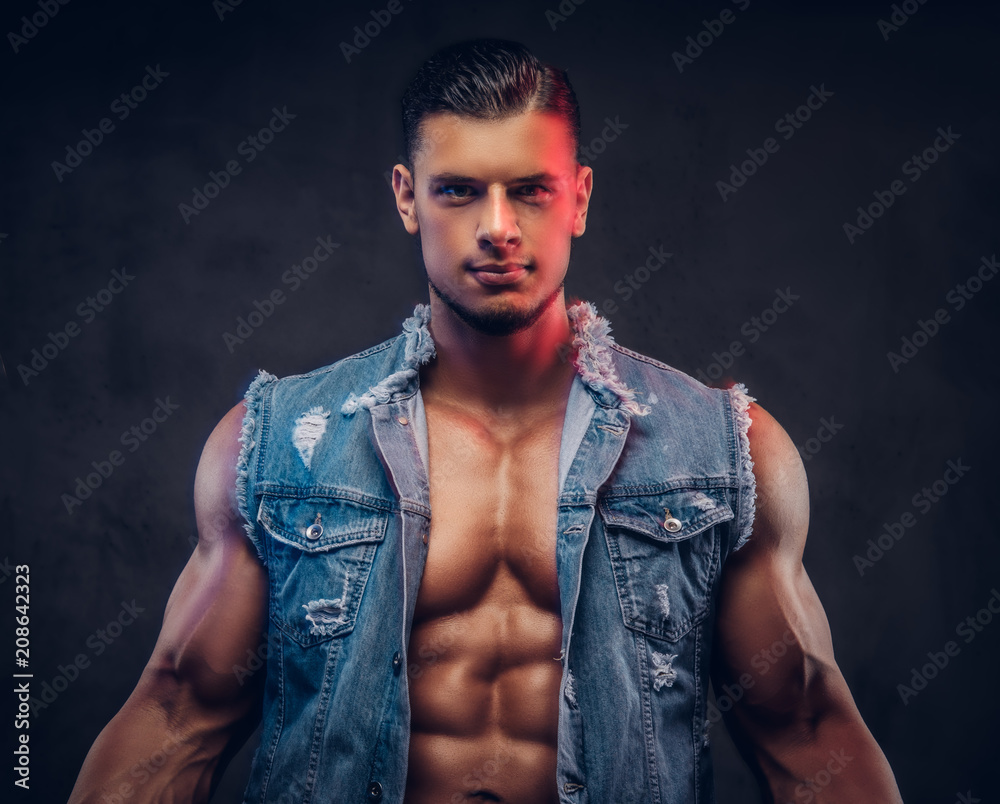 Sexy naked fashionable confident male with a muscular body in a denim vest  poses in a studio. Stock Photo | Adobe Stock