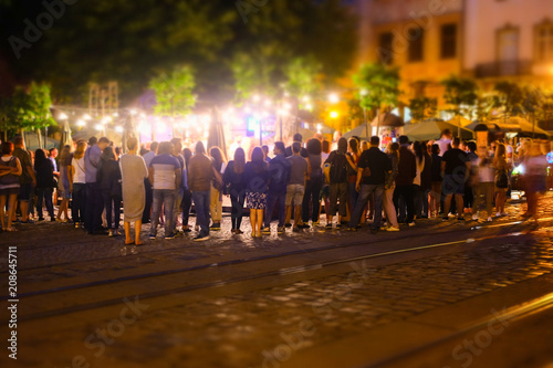 Fototapeta Naklejka Na Ścianę i Meble -  A crowd of people moving on the old european city night street defocused blurred abstract image