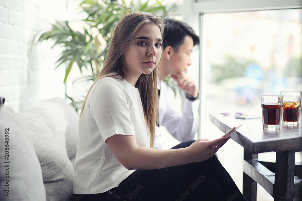 A young Asian businessman is waiting for a partner in a cafe. Bu A young Asian businessman is waiting for a partner in a cafe. Bu