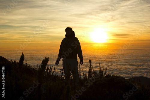 A silhuette of a man with clouds at the background