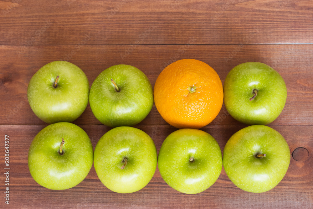 An orange between apples, standing out of the crowd concept. An orange between apples, standing out of the crowd concept.