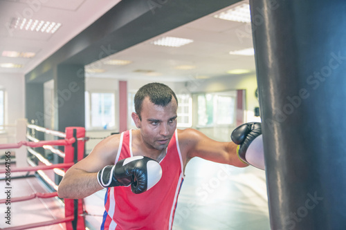 young boxer sportsman performs sports exercises with a boxing pear in the gym.