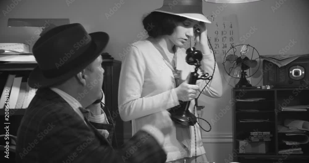 A 1940s newsroom with a female reporter who picks up press camera and exits while her colleague on the phone.