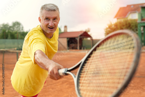 Older man playing recreational tennis for fun © Marko