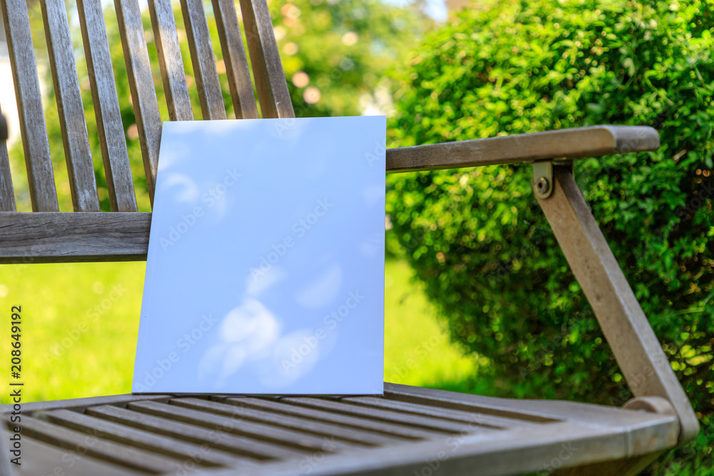 Fototapeta premium Mockup of a magazine cover on a wooden chair in the garden in summer