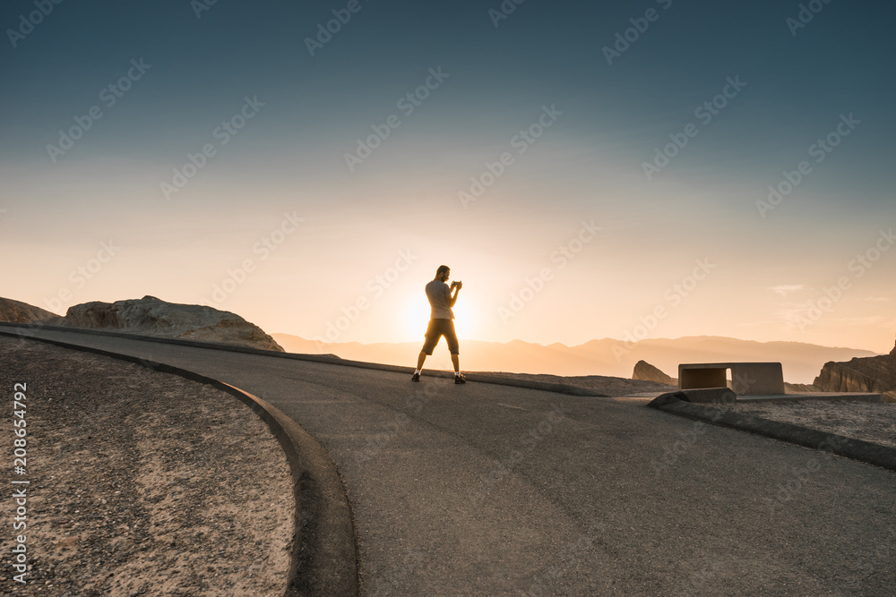 Man taking picture during sunset in the lowest point on earth in Death valley, USA, West Coast
