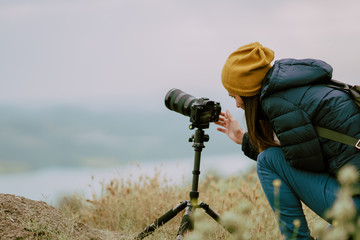young woman shooting with camera at morning.Tripod and mirrorless camera