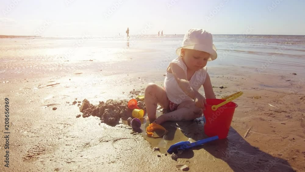 child on the beach playing with sand and toys child on the beach playing with sand and toys