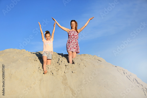 Dwie wesołe dziewczyny skaczą z ogromnej góry piachu.