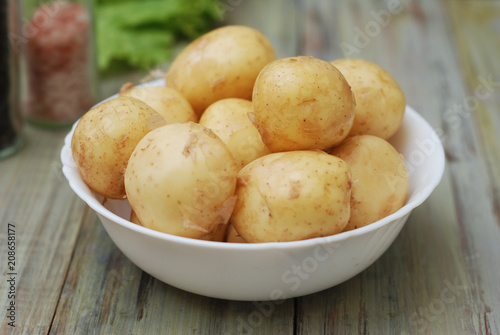 New Raw Potatoes in Bowl on Rustic Wooden table. Close up view, Wooden Spoons, over Wooden Background.