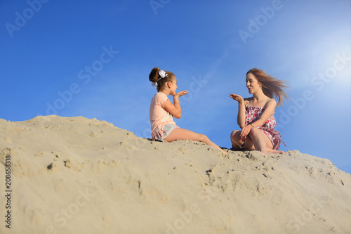 Dwie śliczne dziewczyny przesyłają sobie pocałunki na ogromnej górze piachu.