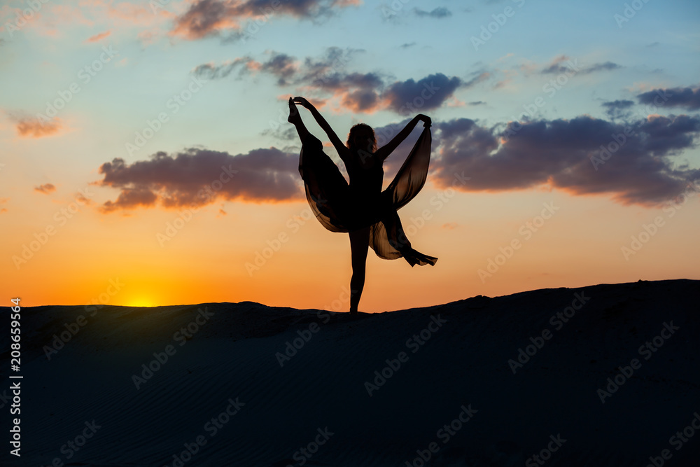 Obraz premium Silhouette of a dancing woman at sunset, she shows performance.
